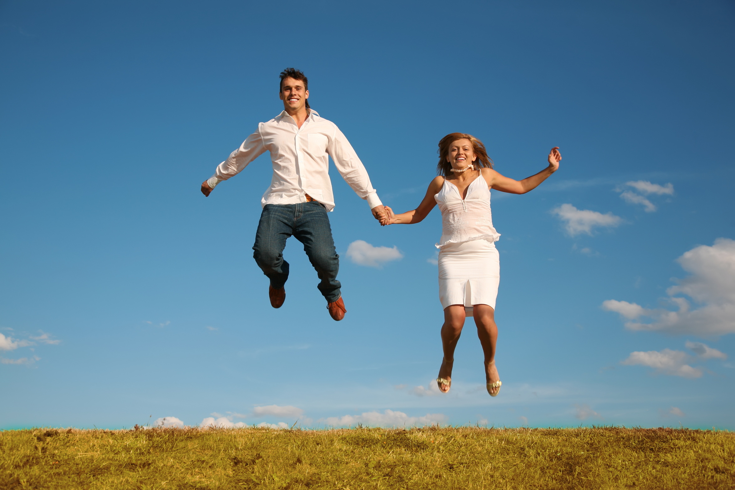 man and woman jumping on the meadow
